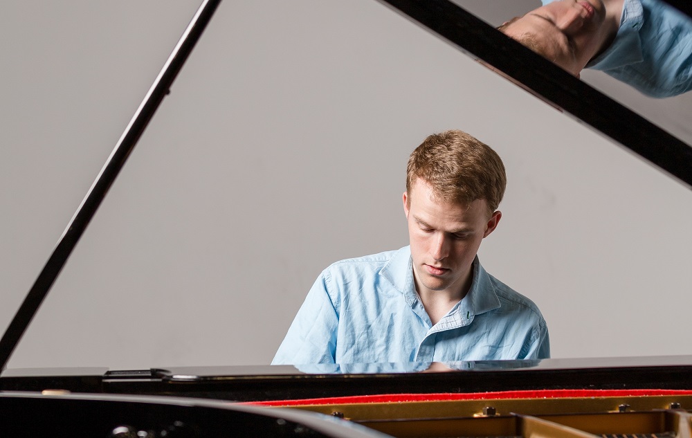 Photo of CJ Madsen playing a grand piano.