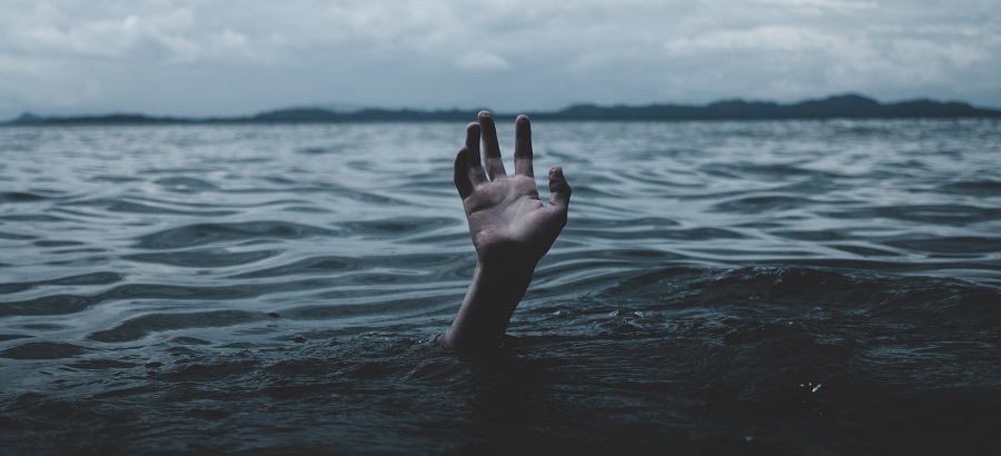 Photo of an outreached hand slipping below the waves